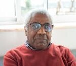 Close-up portrait of a senior man wearing glasses, indoors with natural light.